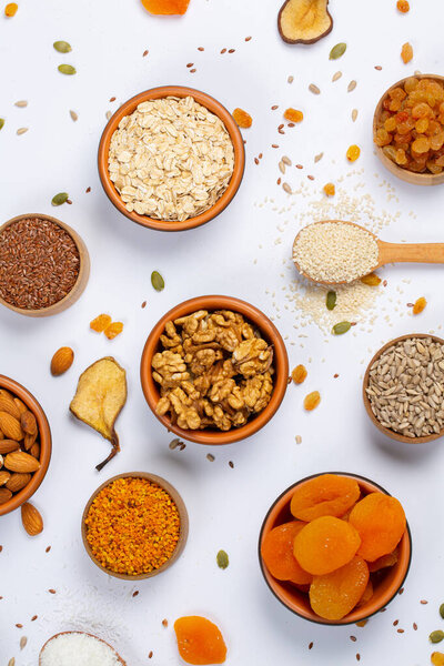 Концепция здорового вегетарианского питания. Ассортимент сухофруктов, орехов и семян на белом фоне. Вид сверху.