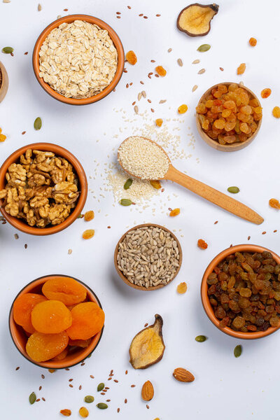 Концепция здорового вегетарианского питания. Ассортимент сухофруктов, орехов и семян на белом фоне. Вид сверху.