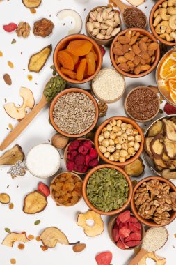 Sağlıklı vejetaryen gıda konsepti. Beyaz arka planda kurutulmuş meyve, fındık ve tohum çeşitleri. Üst görünüm.