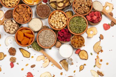 Sağlıklı vejetaryen gıda konsepti. Beyaz arka planda kurutulmuş meyve, fındık ve tohum çeşitleri. Üst görünüm.