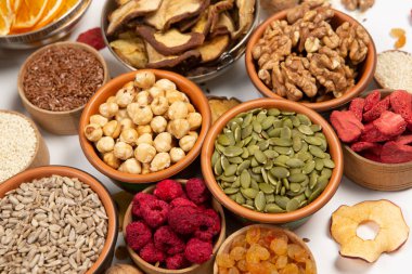 Sağlıklı vejetaryen gıda konsepti. Beyaz arka planda kurutulmuş meyve, fındık ve tohum çeşitleri. Üst görünüm.