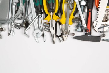 Beyaz arka plandaki bir çantada tamir için gerekli aletler. Çeşitli iş ya da inşaat aletleri. Anahtarlar, pense, tornavida. Üst görünüm