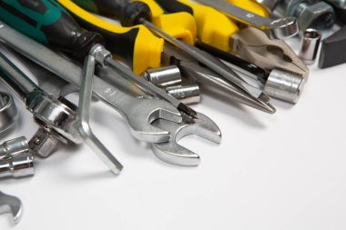 Beyaz arka plandaki bir çantada tamir için gerekli aletler. Çeşitli iş ya da inşaat aletleri. Anahtarlar, pense, tornavida. Üst görünüm