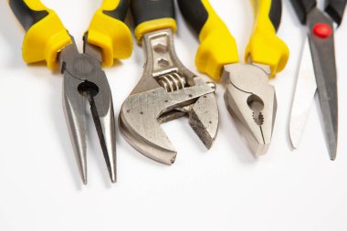 Beyaz arka plandaki bir çantada tamir için gerekli aletler. Çeşitli iş ya da inşaat aletleri. Anahtarlar, pense, tornavida. Üst görünüm