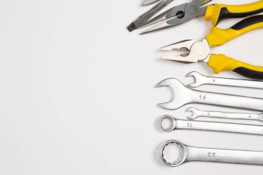 Beyaz arka plandaki bir çantada tamir için gerekli aletler. Çeşitli iş ya da inşaat aletleri. Anahtarlar, pense, tornavida. Üst görünüm