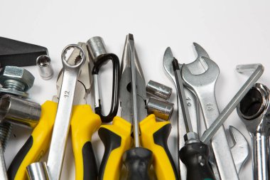 Beyaz arka plandaki bir çantada tamir için gerekli aletler. Çeşitli iş ya da inşaat aletleri. Anahtarlar, pense, tornavida. Üst görünüm