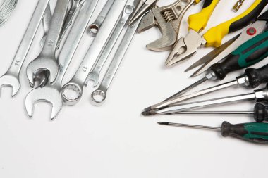 Beyaz arka plandaki bir çantada tamir için gerekli aletler. Çeşitli iş ya da inşaat aletleri. Anahtarlar, pense, tornavida. Üst görünüm