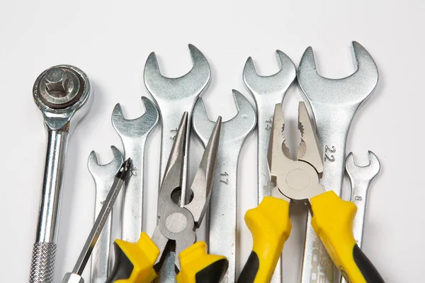 Beyaz arka plandaki bir çantada tamir için gerekli aletler. Çeşitli iş ya da inşaat aletleri. Anahtarlar, pense, tornavida. Üst görünüm