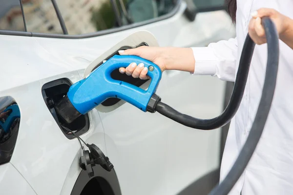 stock image Young business woman refueling her electric car at a EV charging station. Concept of environmentally friendly vehicle. Electric car concept. Green travelling.