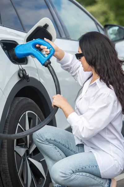 stock image Young business woman refueling her electric car at a EV charging station. Concept of environmentally friendly vehicle. Electric car concept. Green travelling.