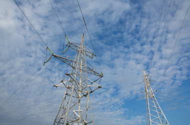 Gün batımında yüksek voltajlı elektrik hatları. Elektrik dağıtım istasyonu. Gökyüzünün arka planında elektrik direkleri