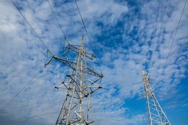 Gün batımında yüksek voltajlı elektrik hatları. Elektrik dağıtım istasyonu. Gökyüzünün arka planında elektrik direkleri