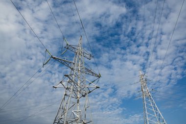 Gün batımında yüksek voltajlı elektrik hatları. Elektrik dağıtım istasyonu. Gökyüzünün arka planında elektrik direkleri