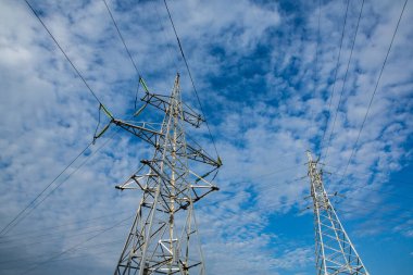 Gün batımında yüksek voltajlı elektrik hatları. Elektrik dağıtım istasyonu. Gökyüzünün arka planında elektrik direkleri