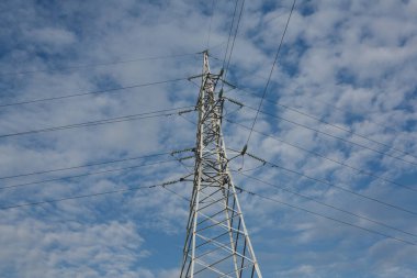 Gün batımında yüksek voltajlı elektrik hatları. Elektrik dağıtım istasyonu. Gökyüzünün arka planında elektrik direkleri