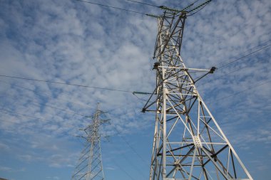 Gün batımında yüksek voltajlı elektrik hatları. Elektrik dağıtım istasyonu. Gökyüzünün arka planında elektrik direkleri