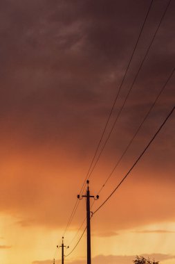 Gün batımında yüksek voltajlı elektrik hatları. Elektrik dağıtım istasyonu. Gökyüzünün arka planında elektrik direkleri