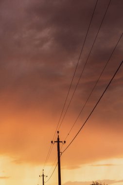 Gün batımında yüksek voltajlı elektrik hatları. Elektrik dağıtım istasyonu. Gökyüzünün arka planında elektrik direkleri