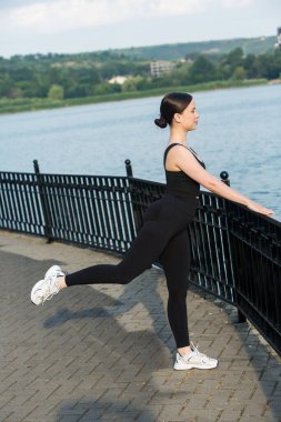 Siyah spor giysili genç bir kadın dışarıda egzersiz yapıyor. Fitness ve sağlıklı yaşam tarzı konsepti. Beyaz kız parkta spor yapıyor..