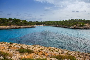 Güzel gün batımı plaj manzarası, egzotik tropik ada doğası, mavi deniz suyu, okyanus dalgaları, renkli kırmızı gökyüzü, Mallorca, İspanya 'da yaz tatili