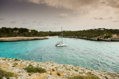 Güzel gün batımı plaj manzarası, egzotik tropik ada doğası, mavi deniz suyu, okyanus dalgaları, renkli kırmızı gökyüzü, Mallorca, İspanya 'da yaz tatili