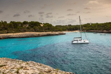 Güzel gün batımı plaj manzarası, egzotik tropik ada doğası, mavi deniz suyu, okyanus dalgaları, renkli kırmızı gökyüzü, Mallorca, İspanya 'da yaz tatili