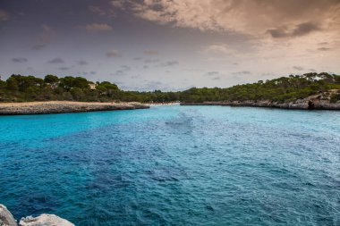 Güzel gün batımı plaj manzarası, egzotik tropik ada doğası, mavi deniz suyu, okyanus dalgaları, renkli kırmızı gökyüzü, Mallorca, İspanya 'da yaz tatili