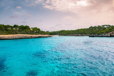 Güzel gün batımı plaj manzarası, egzotik tropik ada doğası, mavi deniz suyu, okyanus dalgaları, renkli kırmızı gökyüzü, Mallorca, İspanya 'da yaz tatili
