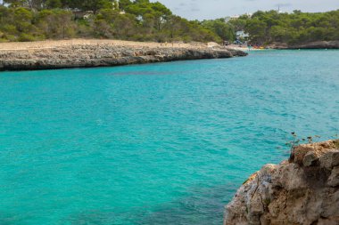 Güzel gün batımı plaj manzarası, egzotik tropik ada doğası, mavi deniz suyu, okyanus dalgaları, renkli kırmızı gökyüzü, Mallorca, İspanya 'da yaz tatili