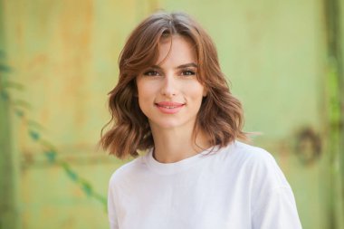 Gülümseyen ve kameraya bakan güzel bir genç kadının portresini yakından çek. Güzel gülüşlü beyaz Avrupalı kız