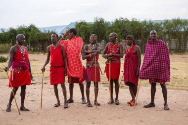 Masai geleneksel renkli giysiler içinde Masai 'nin ünlü Safari seyahat merkezinin yakınındaki yerel bir kabile köyünde dans ettiğini gösteriyor. Kenya. Yazı