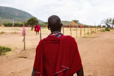 Masai geleneksel renkli giysiler içinde Masai 'nin ünlü Safari seyahat merkezinin yakınındaki yerel bir kabile köyünde dans ettiğini gösteriyor. Kenya. Yazı