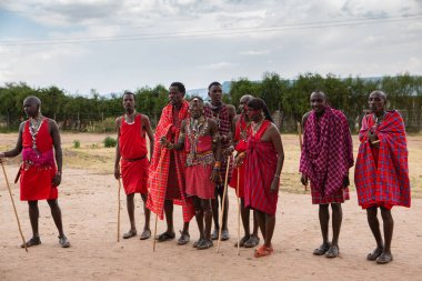 Masai geleneksel renkli giysiler içinde Masai 'nin ünlü Safari seyahat merkezinin yakınındaki yerel bir kabile köyünde dans ettiğini gösteriyor. Kenya. Yazı
