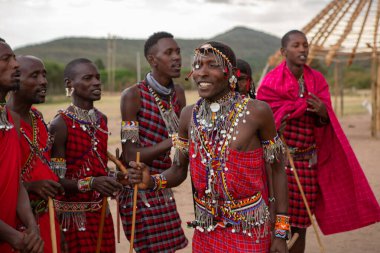 Masai geleneksel renkli giysiler içinde Masai 'nin ünlü Safari seyahat merkezinin yakınındaki yerel bir kabile köyünde dans ettiğini gösteriyor. Kenya. Yazı
