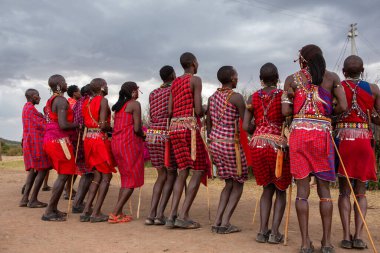 Masai geleneksel renkli giysiler içinde Masai 'nin ünlü Safari seyahat merkezinin yakınındaki yerel bir kabile köyünde dans ettiğini gösteriyor. Kenya. Yazı