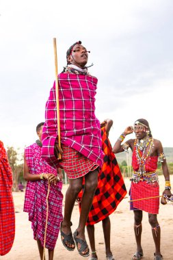 Masai geleneksel renkli giysiler içinde Masai 'nin ünlü Safari seyahat merkezinin yakınındaki yerel bir kabile köyünde dans ettiğini gösteriyor. Kenya. Yazı