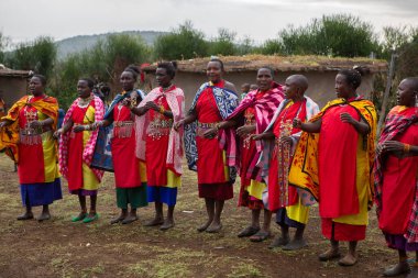 Masai geleneksel renkli giysiler içinde Masai 'nin ünlü Safari seyahat merkezinin yakınındaki yerel bir kabile köyünde dans ettiğini gösteriyor. Kenya. Yazı
