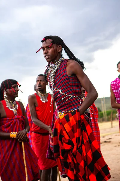 Masai geleneksel renkli giysiler içinde Masai 'nin ünlü Safari seyahat merkezinin yakınındaki yerel bir kabile köyünde dans ettiğini gösteriyor. Kenya. Yazı