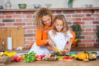 Anne ve kızı mutfakta birlikte yemek pişiriyorlar. Sağlıklı gıda konsepti. Mutlu aile portresi ve taze meyve suyu..