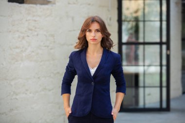 Modern iş binasının önünde başarılı bir iş kadınının portresi. Genç yönetici dışarıda poz veriyor. Ofisin kadın çalışanı..