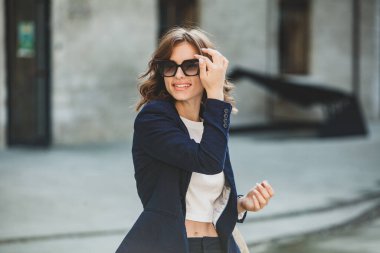 Modern iş binasının önünde başarılı bir iş kadınının portresi. Genç yönetici dışarıda poz veriyor. Ofisin kadın çalışanı..