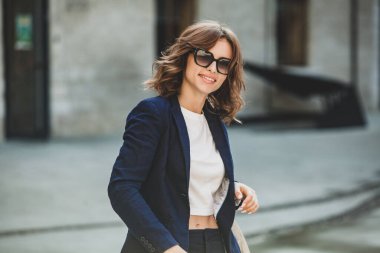 Modern iş binasının önünde başarılı bir iş kadınının portresi. Genç yönetici dışarıda poz veriyor. Ofisin kadın çalışanı..