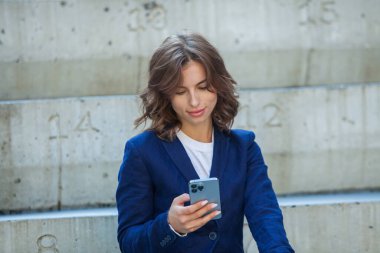 Modern iş binasının önünde başarılı bir iş kadınının portresi. Genç yönetici dışarıda poz veriyor. Ofisin kadın çalışanı..