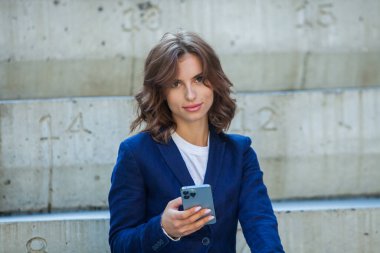 Modern iş binasının önünde başarılı bir iş kadınının portresi. Genç yönetici dışarıda poz veriyor. Ofisin kadın çalışanı..