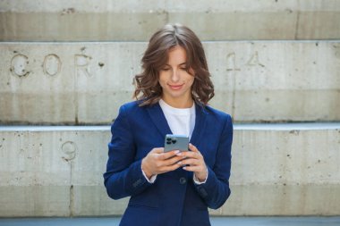 Modern iş binasının önünde başarılı bir iş kadınının portresi. Genç yönetici dışarıda poz veriyor. Ofisin kadın çalışanı..