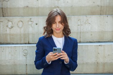 Modern iş binasının önünde başarılı bir iş kadınının portresi. Genç yönetici dışarıda poz veriyor. Ofisin kadın çalışanı..