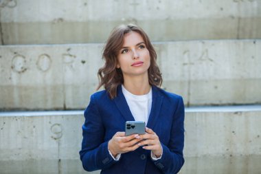 Modern iş binasının önünde başarılı bir iş kadınının portresi. Genç yönetici dışarıda poz veriyor. Ofisin kadın çalışanı..