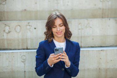 Modern iş binasının önünde başarılı bir iş kadınının portresi. Genç yönetici dışarıda poz veriyor. Ofisin kadın çalışanı..