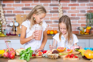 Mutfakta taze sebzelerle iki küçük kız. Sağlıklı gıda konsepti. Mutlu kardeşler..