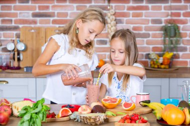 Mutfakta taze sebzelerle iki küçük kız. Sağlıklı gıda konsepti. Mutlu kardeşler..